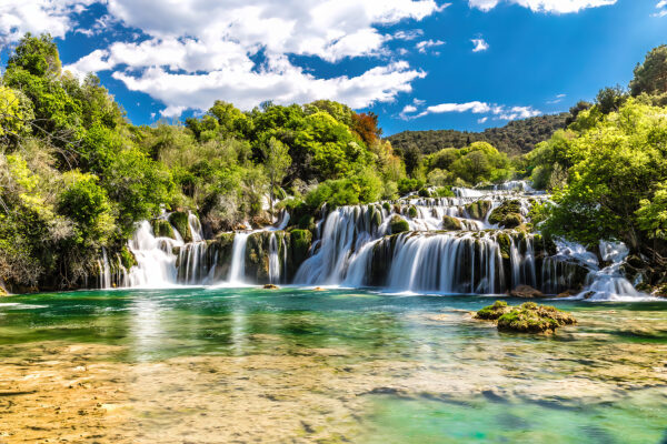 El Parque Nacional de Krka rodeado de árboles y un cielo azul El Parque Nacional de Krka rodeado de árboles y un cielo azul