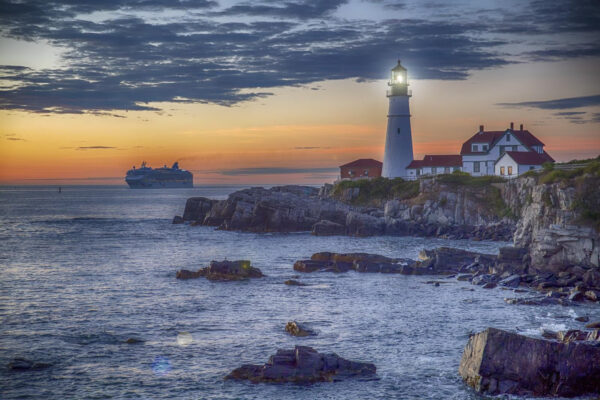 Faro en una costa rocosa con un crucero al fondo Faro en una costa rocosa con un crucero al fondo