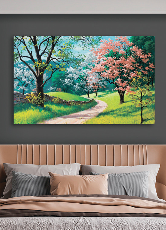 A dirt road through a grassy field with trees and a stone wall