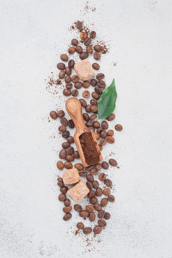 A spoon with coffee beans and sugar on top A spoon with coffee beans and sugar on top