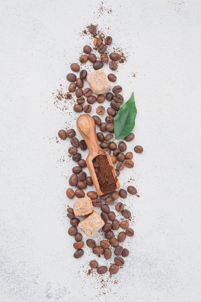 A spoon with coffee beans and sugar on top A spoon with coffee beans and sugar on top