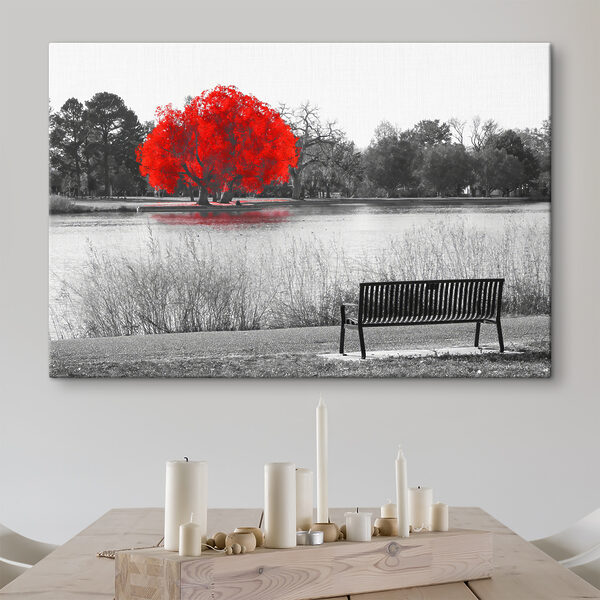 A bench by a lake with a red tree A bench by a lake with a red tree