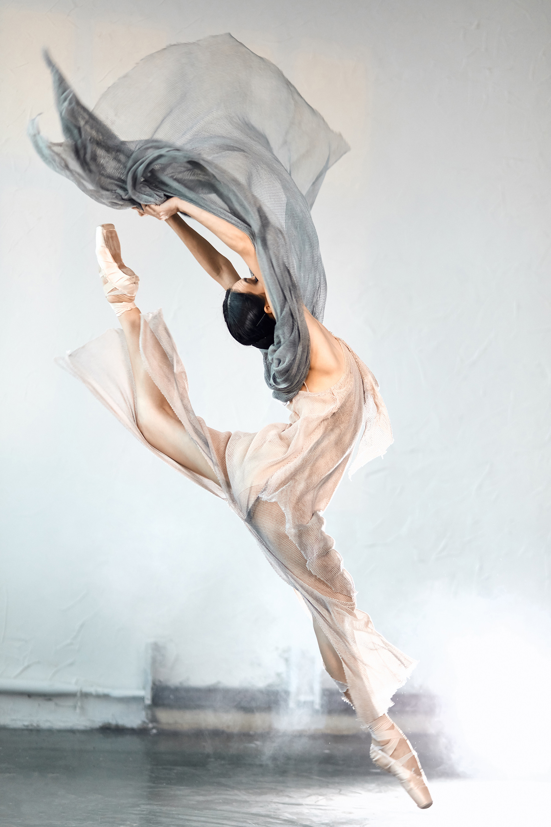 A woman in a dress and pointe shoes jumping in the air