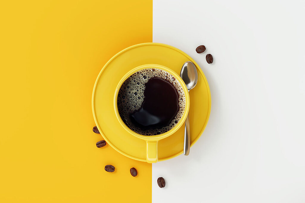 A yellow cup of coffee and beans