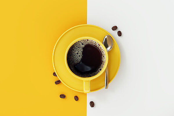 A yellow cup of coffee and beans