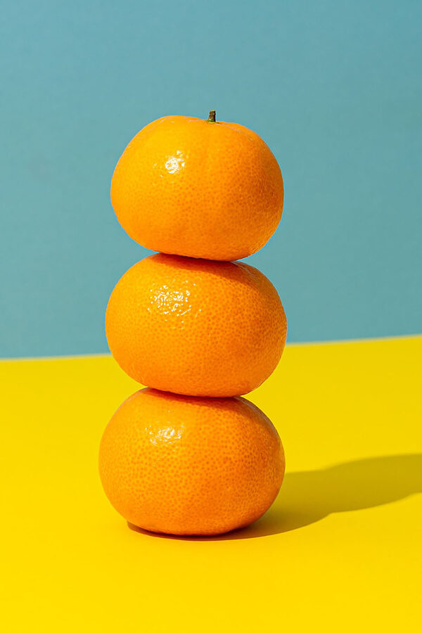 A stack of oranges on a yellow and blue surface