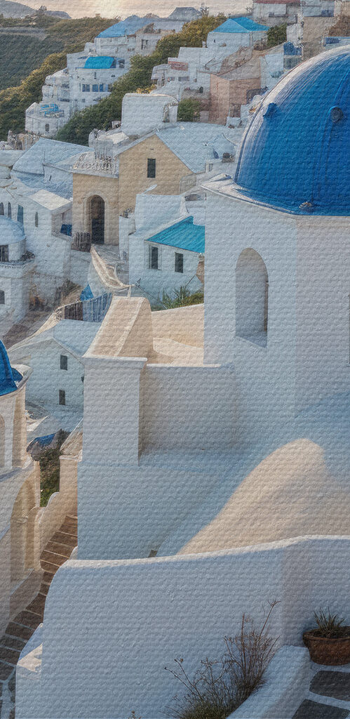 White buildings with blue domes on a hill with a body of water in the background White buildings with blue domes on a hill with a body of water in the background